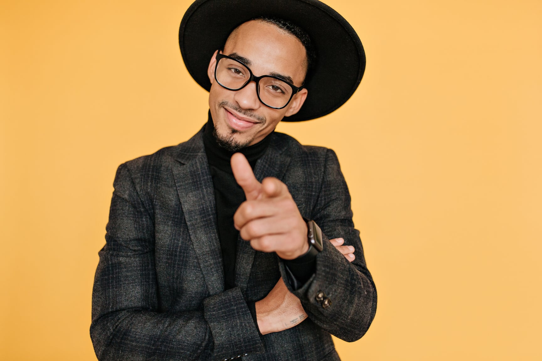 Smiling Confident African Man Pointing Finger to Camera. Studio Portrait of Handsome Male Model with Brown Skin Isolated on Yellow Background..